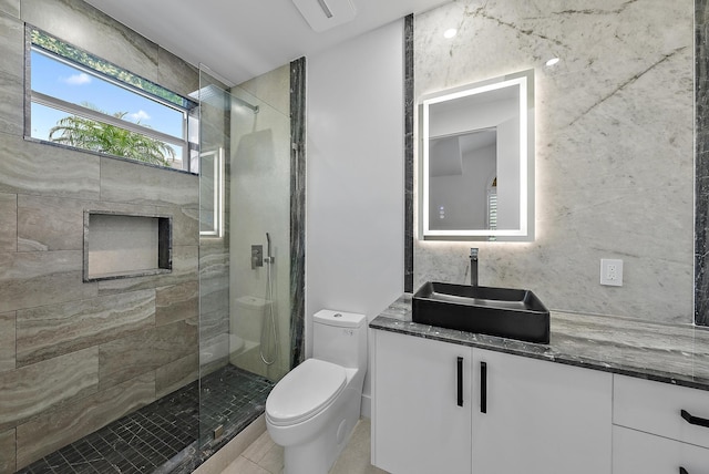 bathroom featuring tiled shower, tile patterned floors, vanity, and toilet