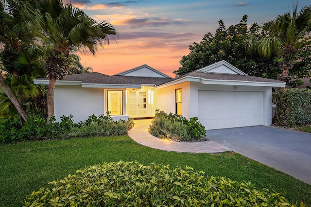 single story home with a garage and a lawn