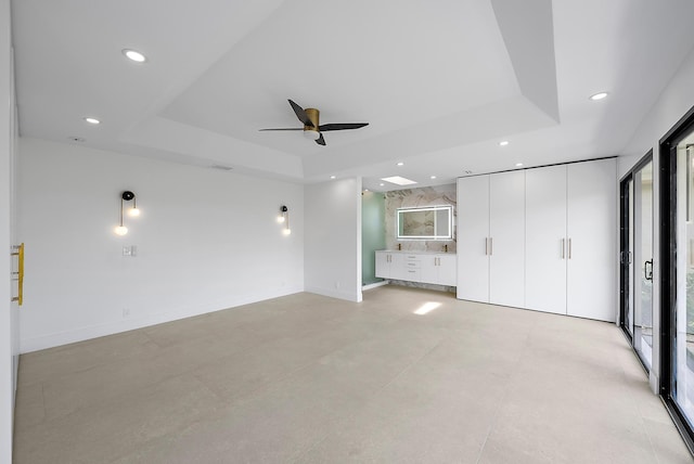 interior space featuring a raised ceiling and ceiling fan