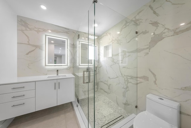 bathroom featuring vanity, toilet, a shower with door, and tile walls