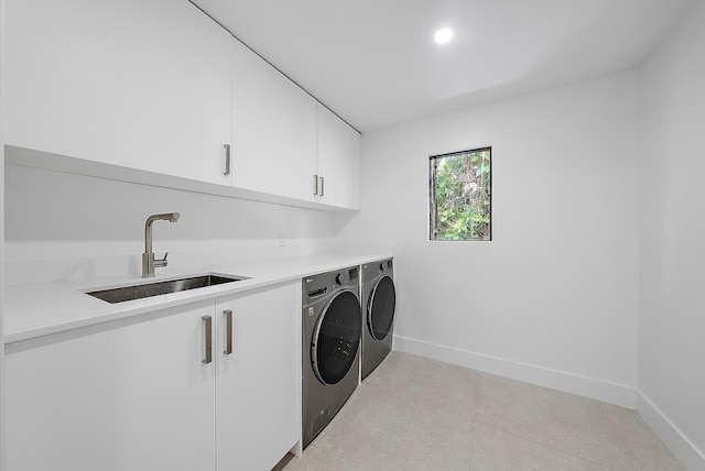 clothes washing area with cabinets, separate washer and dryer, and sink