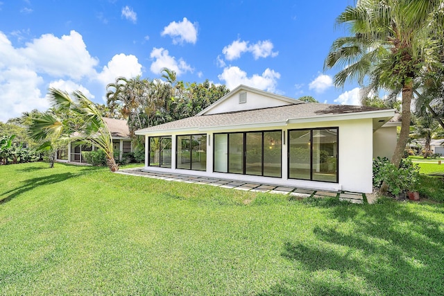 rear view of property featuring a sunroom and a lawn