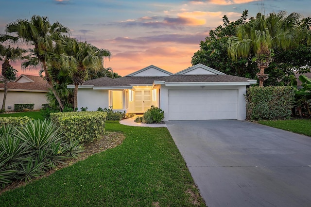 ranch-style house with a garage and a lawn