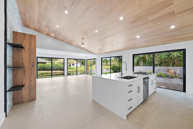 kitchen featuring tasteful backsplash, a kitchen island with sink, sink, light tile patterned floors, and white cabinets