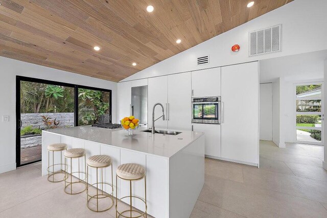 kitchen featuring appliances with stainless steel finishes, lofted ceiling, white cabinetry, sink, and wood ceiling