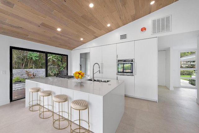 kitchen featuring sink, wood ceiling, stainless steel oven, a large island, and white cabinets