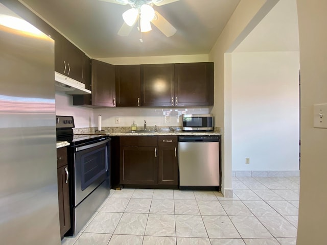 kitchen featuring appliances with stainless steel finishes, light stone counters, light tile patterned floors, dark brown cabinetry, and ceiling fan