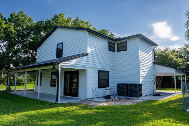 back of house featuring central air condition unit and a lawn