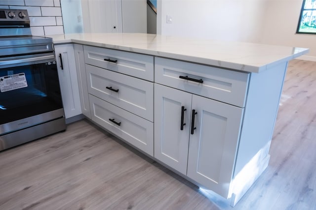 kitchen featuring stainless steel electric range oven, white cabinets, tasteful backsplash, and light wood-type flooring