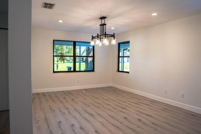 empty room featuring a notable chandelier and wood-type flooring