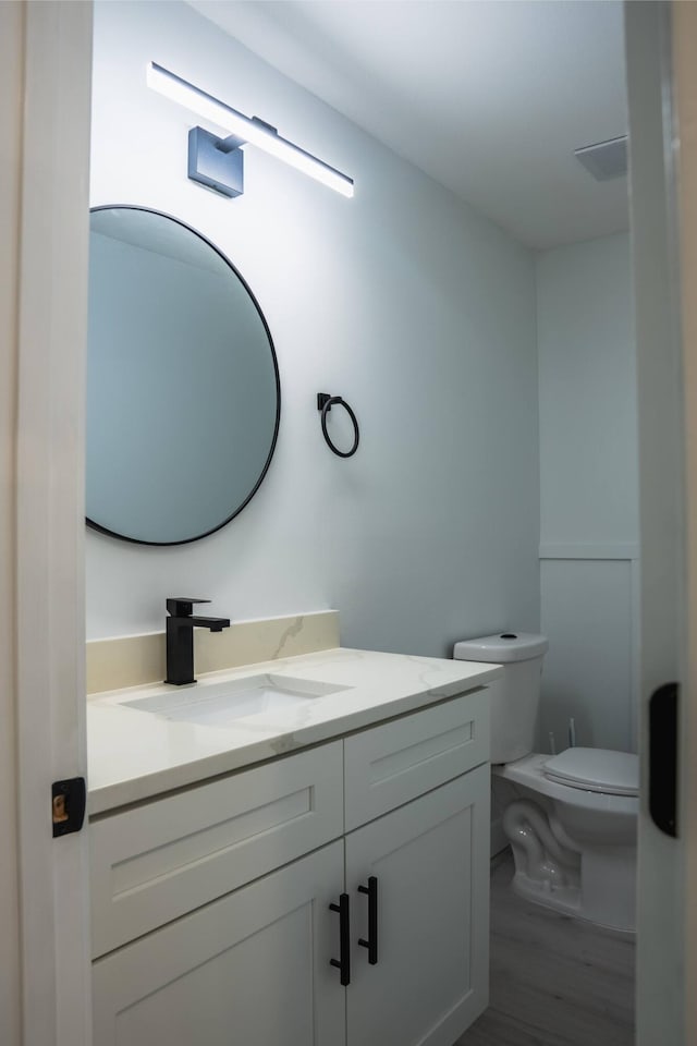 bathroom with wood-type flooring, toilet, and vanity