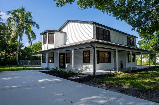 farmhouse-style home featuring covered porch and a front yard