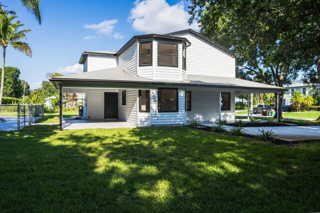 rear view of property featuring a carport and a yard