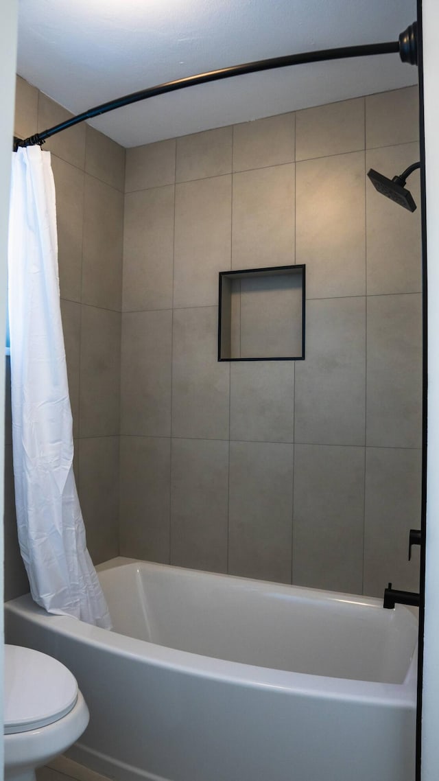 bathroom featuring toilet and shower / bath combination with curtain