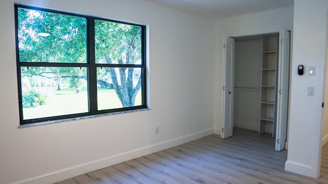 unfurnished bedroom with a closet, multiple windows, and light hardwood / wood-style flooring