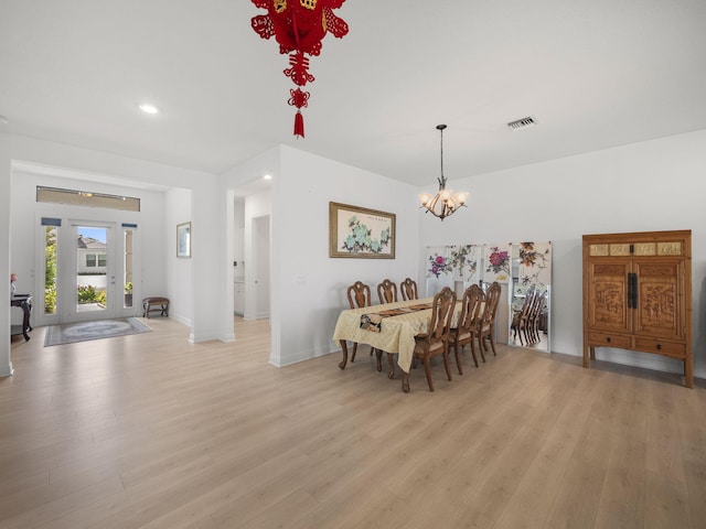 dining space with a notable chandelier and light hardwood / wood-style flooring