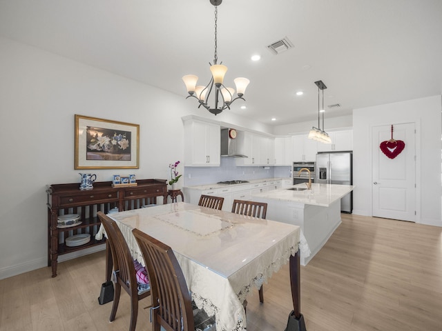 dining space featuring sink, light hardwood / wood-style floors, and a notable chandelier