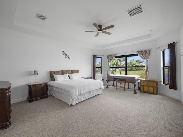 carpeted bedroom with a tray ceiling and ceiling fan