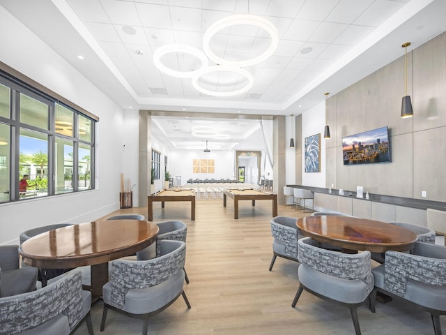 dining area featuring a raised ceiling and light hardwood / wood-style flooring