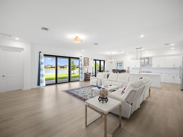 living room with light hardwood / wood-style floors and an inviting chandelier