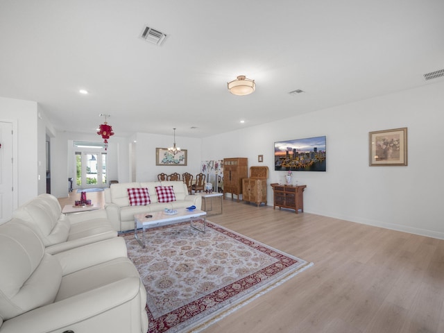 living room with light hardwood / wood-style floors and a notable chandelier