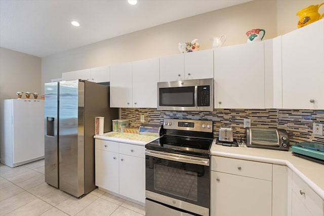 kitchen with tasteful backsplash, appliances with stainless steel finishes, light tile patterned floors, and white cabinets