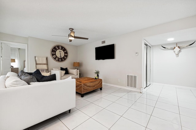 living room with ceiling fan, light tile patterned flooring, visible vents, and baseboards