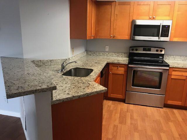 kitchen featuring light hardwood / wood-style floors, light stone counters, appliances with stainless steel finishes, and sink