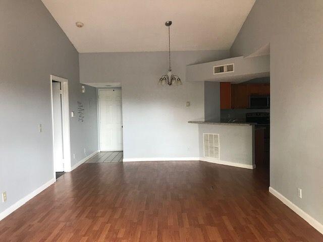 unfurnished living room with hardwood / wood-style flooring, high vaulted ceiling, and an inviting chandelier