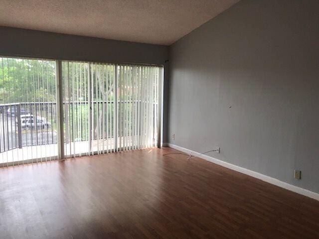 empty room featuring hardwood / wood-style flooring, a healthy amount of sunlight, and vaulted ceiling