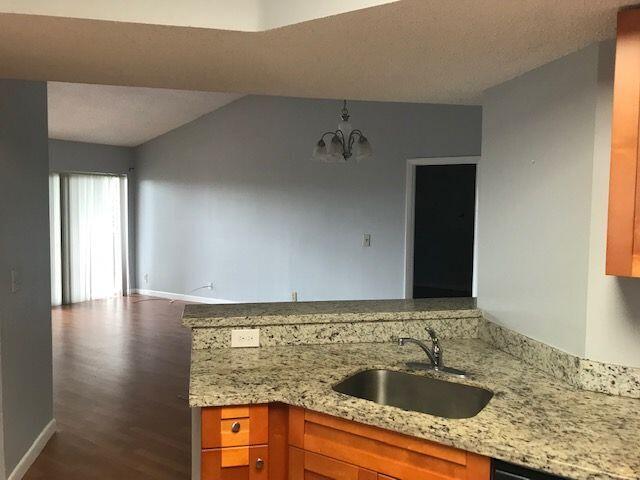 kitchen with a chandelier, hardwood / wood-style floors, sink, light stone counters, and kitchen peninsula