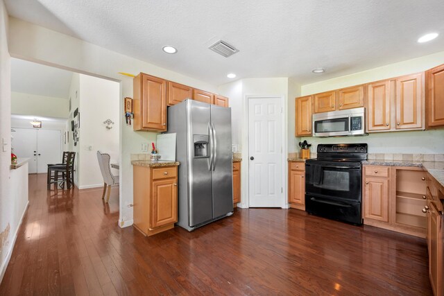 kitchen featuring a textured ceiling, light brown cabinetry, dark hardwood / wood-style floors, and stainless steel appliances