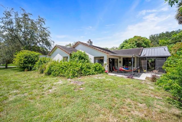 back of house with a yard, a sunroom, and a patio area