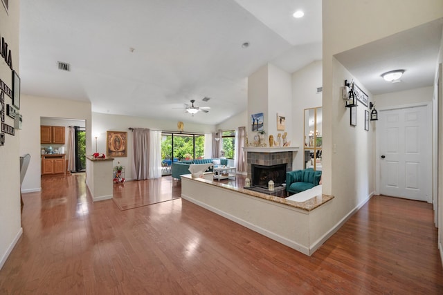 unfurnished living room featuring a tile fireplace, ceiling fan, lofted ceiling, and wood-type flooring