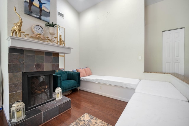 bedroom featuring a tile fireplace and dark hardwood / wood-style flooring