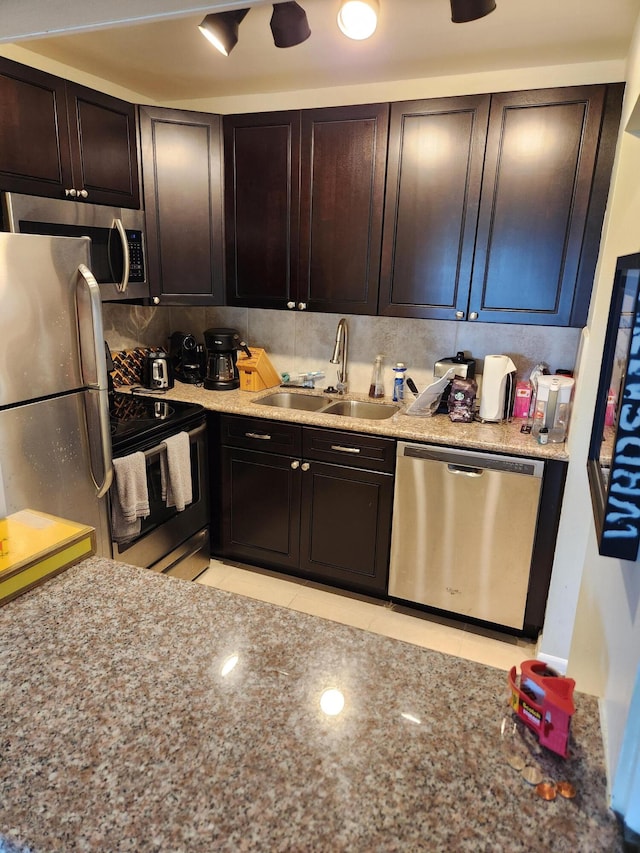 kitchen with decorative backsplash, stainless steel appliances, light stone countertops, and sink