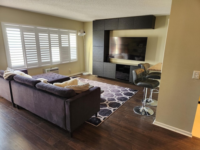 living room featuring an AC wall unit, a textured ceiling, dark hardwood / wood-style floors, and plenty of natural light