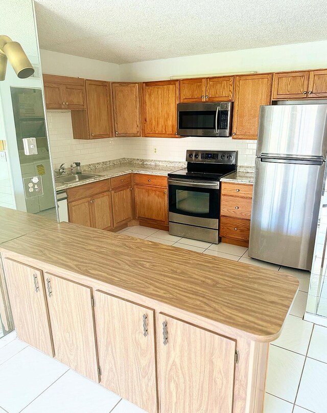 kitchen with light tile patterned floors, appliances with stainless steel finishes, sink, and decorative backsplash