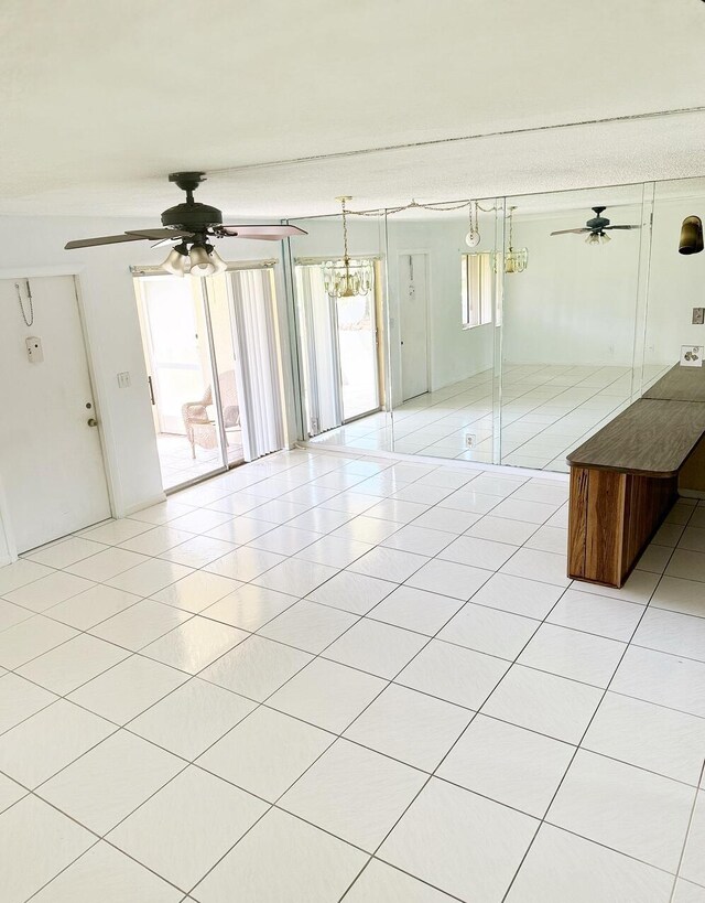 unfurnished bedroom with ceiling fan with notable chandelier and light tile patterned flooring