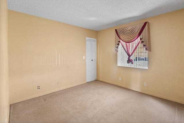 empty room with a textured ceiling and light carpet