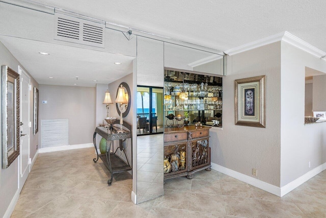 bar with crown molding, a textured ceiling, and light tile patterned floors