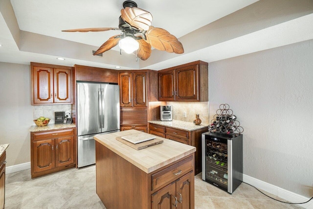 kitchen featuring stainless steel fridge, ceiling fan, tasteful backsplash, a kitchen island, and beverage cooler