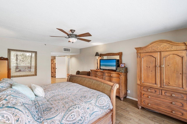 bedroom with a textured ceiling, ceiling fan, and light hardwood / wood-style floors