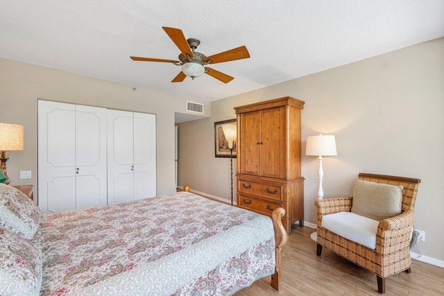 bedroom featuring a textured ceiling, light hardwood / wood-style floors, a closet, and ceiling fan