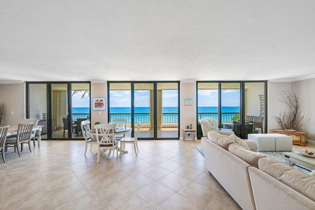 living room with expansive windows, crown molding, a water view, and a textured ceiling