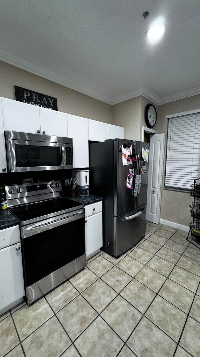 kitchen with white cabinetry, stainless steel appliances, ornamental molding, and light tile patterned floors