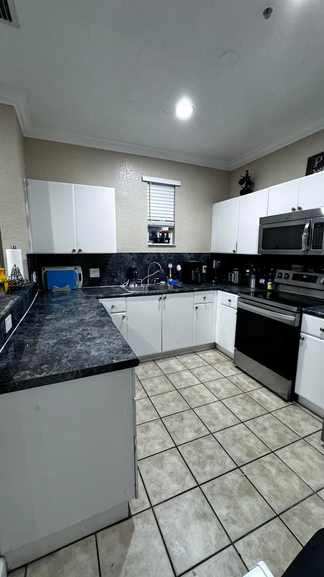 kitchen featuring light tile patterned flooring, stainless steel appliances, backsplash, and crown molding