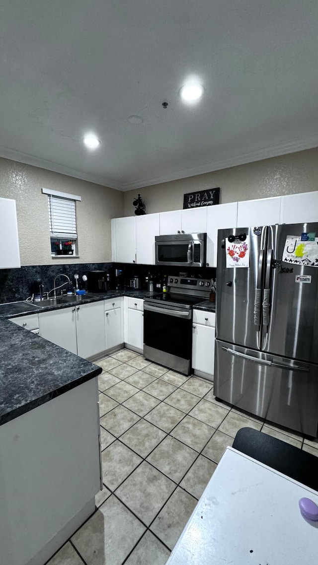 kitchen with tasteful backsplash, stainless steel appliances, sink, light tile patterned floors, and white cabinetry