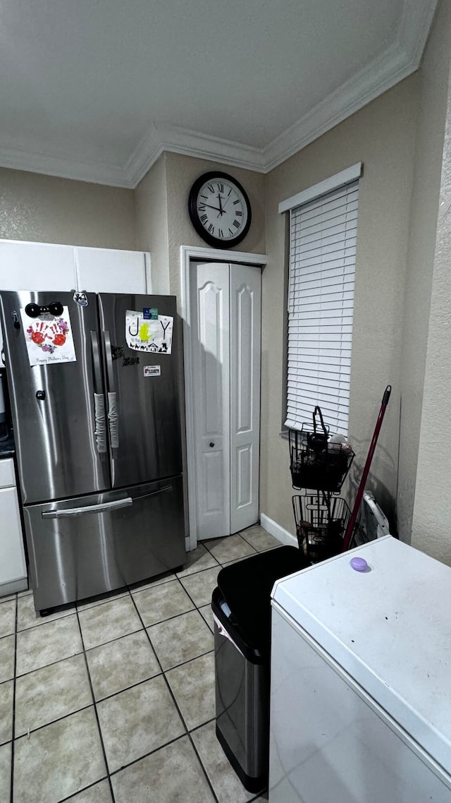 laundry area featuring light tile patterned floors and crown molding