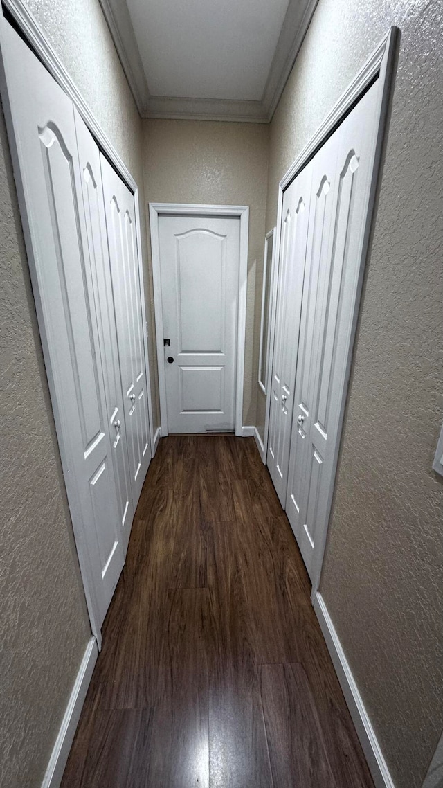 corridor with ornamental molding and dark wood-type flooring